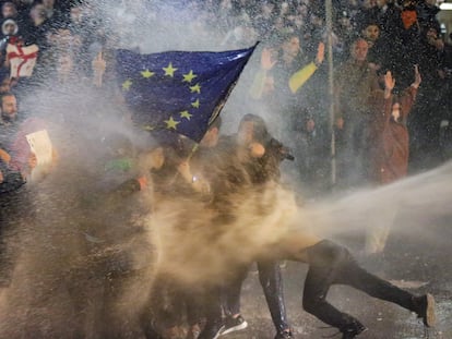 Manifestantes que portan una bandera de la Unión Europea son rociados con un cañón de agua por la policía antidisturbios de Georgia, en Tbilisi, el 7 de marzo de 2023.