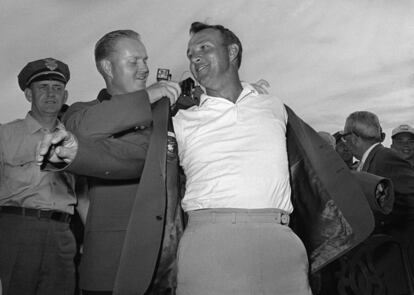 Arnold Palmer en 1964, colocándose la chaqueta con la ayuda de Jack Nicklaus tras ganar el torneo de los Masters de Augusta, en Georgia (EE.UU).
