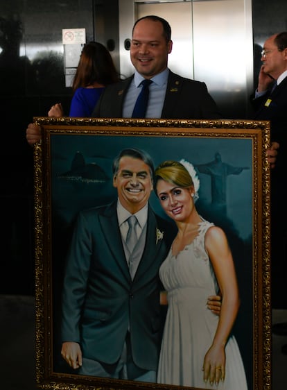 Heitor Freire sostiene un
retrato de Jair Bolsonaro y
su esposa, Michelle, en
febrero de 2019.