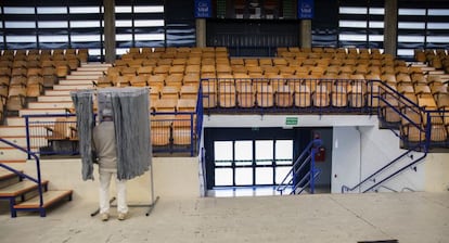 Un hombre elige la papeleta el colegio electoral habiltado en el polideportivo Mendizorrotza de Vitoria