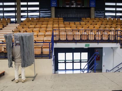 Un hombre elige la papeleta el colegio electoral habiltado en el polideportivo Mendizorrotza de Vitoria