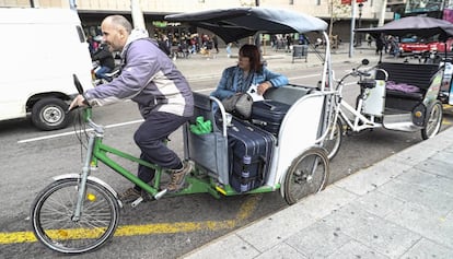 Un bicitaxi en plaza de Cataluña con una turista y sus maletas.