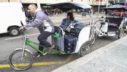 Un bicitaxi en plaza de Catalu&ntilde;a con una turista y sus maletas.