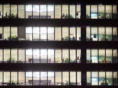 Oficinas de noche con algunos trabajadores todavía en sus puestos en el distrito financiero de las Cuatro Torres en Madrid.