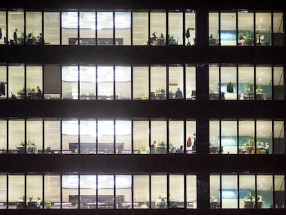 Oficinas de noche con algunos trabajadores todavía en sus puestos en el distrito financiero de las Cuatro Torres en Madrid.