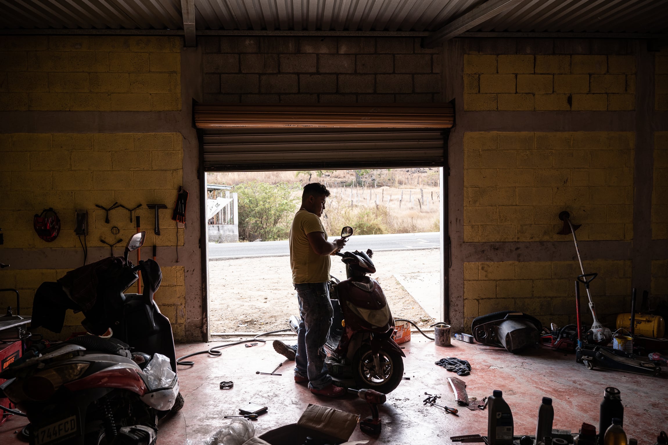Andrés arregla el retrovisor lateral de un scooter en su taller de mecánica, en El Estoraque, aldea Amatón, Quezada, Jutiapa, el 13 de marzo de 2026.