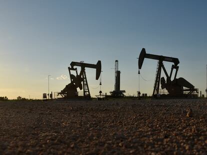 Maquinarias operan frente a una plataforma de perforación en un campo petrolero en Midland, Texas