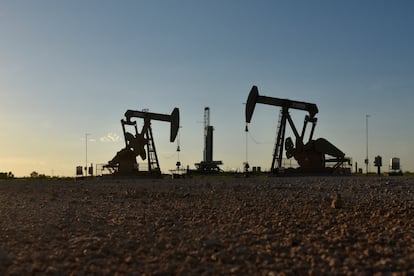 Maquinarias operan frente a una plataforma de perforación en un campo petrolero en Midland, Texas
