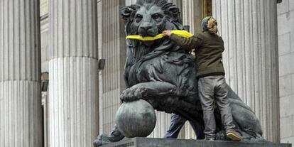 A Greenpeace activist gags one one the stone lions presiding the Spanish Congress to protest the Citizen Safety Law.