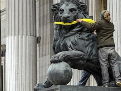 A Greenpeace activist gags one one the stone lions presiding the Spanish Congress to protest the Citizen Safety Law.