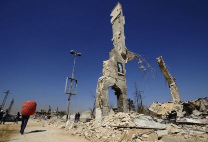 Una imagen del presidente sirio Bashar al-Assad cuelga en la pared de un edificio en ruinas en el barrio de al-Dukhaneya al que comienzan a llegar los vecinos después de ser desocupado por los rebeldes.