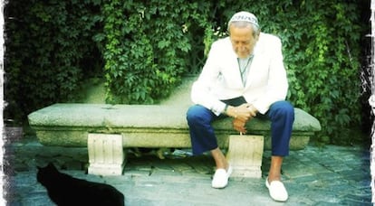 El dise&ntilde;ador Elio Berhanyer junto a un gato negro a la entrada del Jard&iacute;n Bot&aacute;nico de Madrid.
 