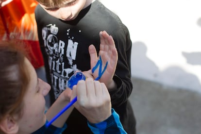 Una adulta pinta la mano de uno de los niños de El Tiemblo (Ávila).