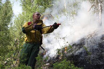 Un bombero vierte agua con una manguera durante las labores de extinción en los bosques del oriente ruso.