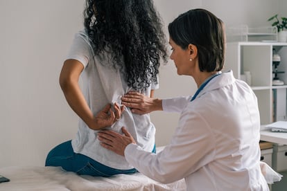 Una doctora examina la espalda a una mujer, en una foto de archivo.