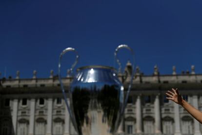 Transeúntes se fotografían junto a una réplica gigante de la copa de la Liga de Campeones a las afueras del Palacio Real en Madrid, el 30 de mayo de 2019. Este sábado 1 de junio se disputará la final de la Champions League entre los equipos ingleses Tottenham y Liverpool, el Wanda Metropolitano de Madrid.