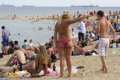 Unos turistas juegan mientras beben en la playa de la Barceloneta. El juego consiste en que, divididos en dos equipos, el que le pega a una botella situada en el centro, bebe trago.