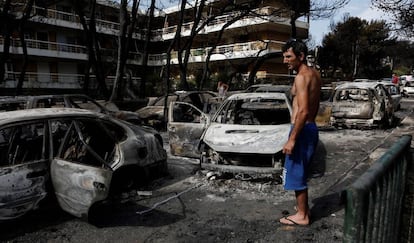 Um homem observa o estado em que ficaram vários carros calcinados em Mati (Grécia), nesta segunda-feira.