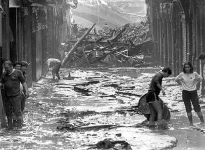 Aspecto que ofrecía la calle Barrenkale Barrena, en el Casco Viejo de Bilbao, tras la riada. Al fondo, el puente de La Ribera, parcialmente destruido.