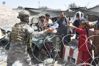 Soldados distribuem água a afegãos acampados na área do aeroporto de Cabul.