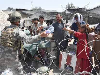 Soldados reparten agua a afganos acampados junto al aeropuerto de Kabul.