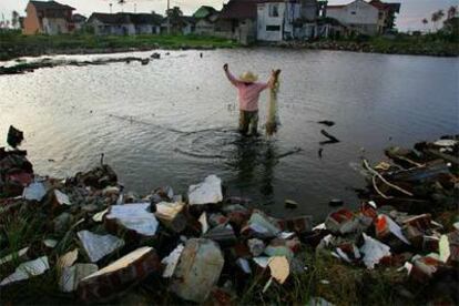 Un hombre pesca con red en lo que antes era una zona residencial de Banda Aceh.