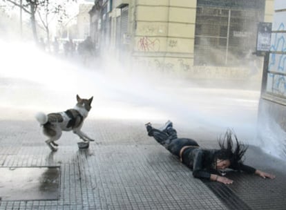 Una estudiante es abatida por un cañón de agua empleado por la policía para disolver a los manifestantes