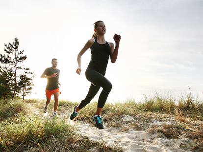 Una mujer y un hombre corriendo por la playa.