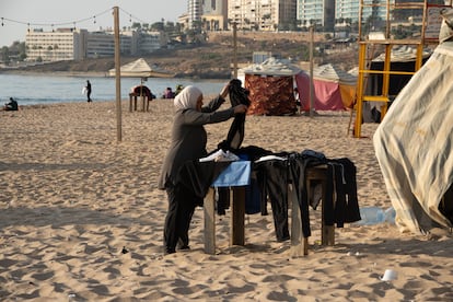 Las personas a menudo se duchan o lavan su ropa usando grandes tanques de agua en la playa. En la imagen, una mujer doblaba su ropa después de secarla al sol, a principios de octubre.