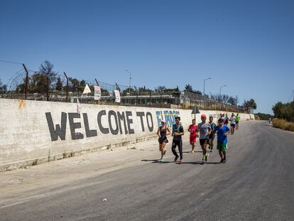 El equipo de corredores de la ONG Yoga y Deporte con Refugiados pasa junto al muro del antiguo campamento de refugiados de Moria, cerrado después del incendio de 2020.