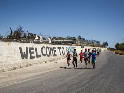 El equipo de corredores de la ONG Yoga y Deporte con Refugiados pasa junto al muro del antiguo campamento de refugiados de Moria, cerrado después del incendio de 2020.