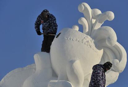 Dos trabajadores moldean una escultura de nieve para el 30 Festival de Harbin, el mayor parque de hielo y nive del mundo.