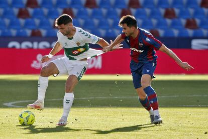 El delantero del Elche Lucas Boyé protege el balón ante el defensa del Levante Sergio Postigo este sábado en el estadio Ciutat de València.