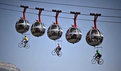Tres ciclistas simulan una carrera en el aire colgados del teleférico Grenoble Bastilla, durante la 17ª etapa del Tour, el 16 de septiembre.