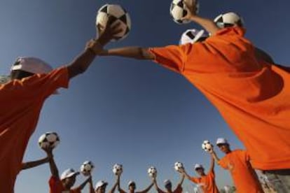 Unos niños sostienen balones de fútbol. EFE/Archivo