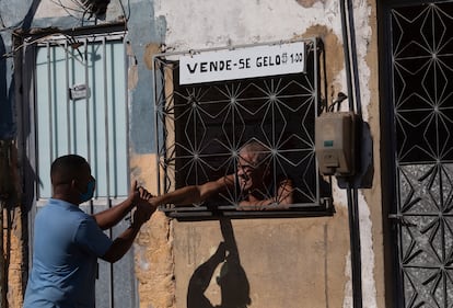 Agente de saneamento cumprimenta morador que vende gelo no Complexo da Maré, no Rio.
