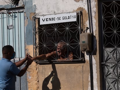 Agente de saneamento cumprimenta morador que vende gelo no Complexo da Maré, no Rio.