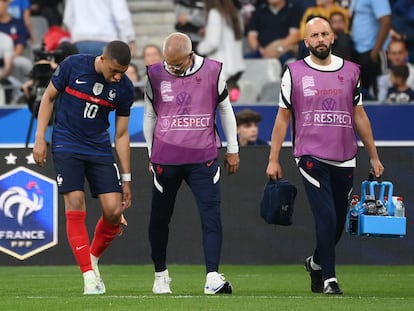 Mbappé se señala la rodilla lesionada ante los médicos de Francia, este viernes en París.