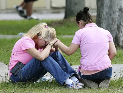 Do mujeres rezan cerca del instituto donde se produjo el tiroteo.