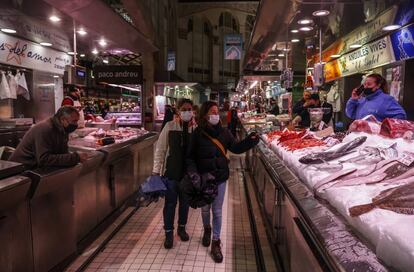 Dos personas pasan por un puesto de pescado en el Mercado Central de Valencia.