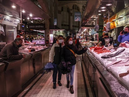 Dos personas pasan por un puesto de pescado en el Mercado Central de Valencia.