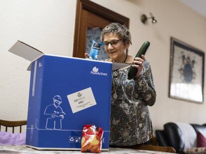 Mª Carmen Clavero, de 84 años, abre el lote de alimentos gratuitos que la iniciativa 'Cestas contra la covid-19' le ha llevado hasta la puerta de su casa.