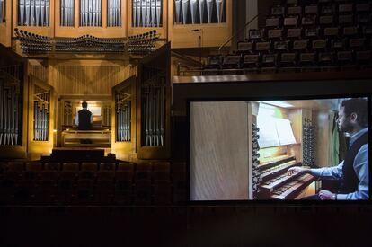 Benjamin Alard durante su recital. A la derecha, la pantalla instalada sobre el escenario en la que pueden verse de cerca las evoluciones de las manos y los pies del organista.