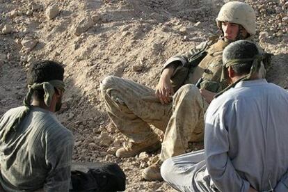 Un <i>marine</i> estadounidense vigila a dos presos iraquíes, maniatados y con los ojos vendados, capturados en Faluya.