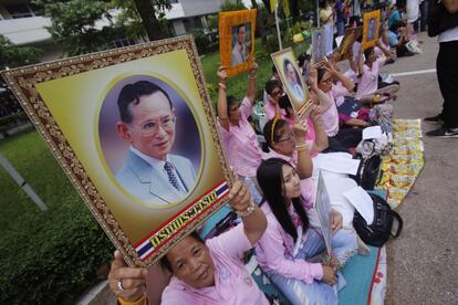 Ciudadanos tailandeses rezan mientras sostienen retratos del rey Bhumibol Adulyadej en el hospital Siriraj, donde el monarca está recibiendo tratamiento. (AP Photo/Sakchai Lalit)
