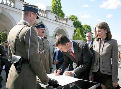 Don Felipe firma, ante doña Letizia, en el libro de visitantes de la tumba del soldado desconocido, en Varsovia.