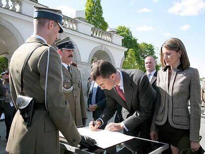 Don Felipe firma, ante doña Letizia, en el libro de visitantes de la tumba del soldado desconocido, en Varsovia.