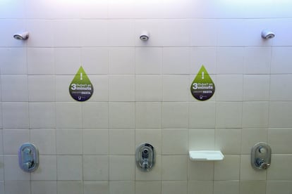 Vista de las duchas del polideportivo municipal del Parque de la España Industrial en Barcelona, con carteles recordando el uso responsable del agua.