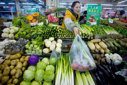 Una mujer vende vegetales en un mercado de Qingdao, en la provincia de Shandong, China.