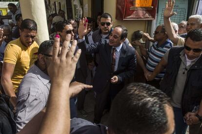 Egypt's ex-army chief and leading presidential candidate Abdel Fattah al-Sisi (C) salutes the crowd after casting his vote at a polling station in the north Cairo district of Heliopolis on May 26, 2014. Egyptians voted for a new president, with the ex-army chief who overthrew the country's first democratically elected leader and crushed his Islamist movement expected to win in a landslide. AFP PHOTO / KHALED DESOUKI